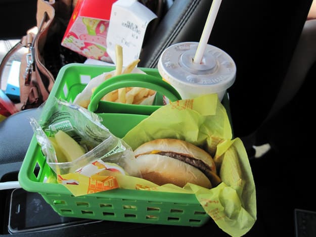 Keep your kids from making a mess when eating in the car by putting their meal into an organization bucket.