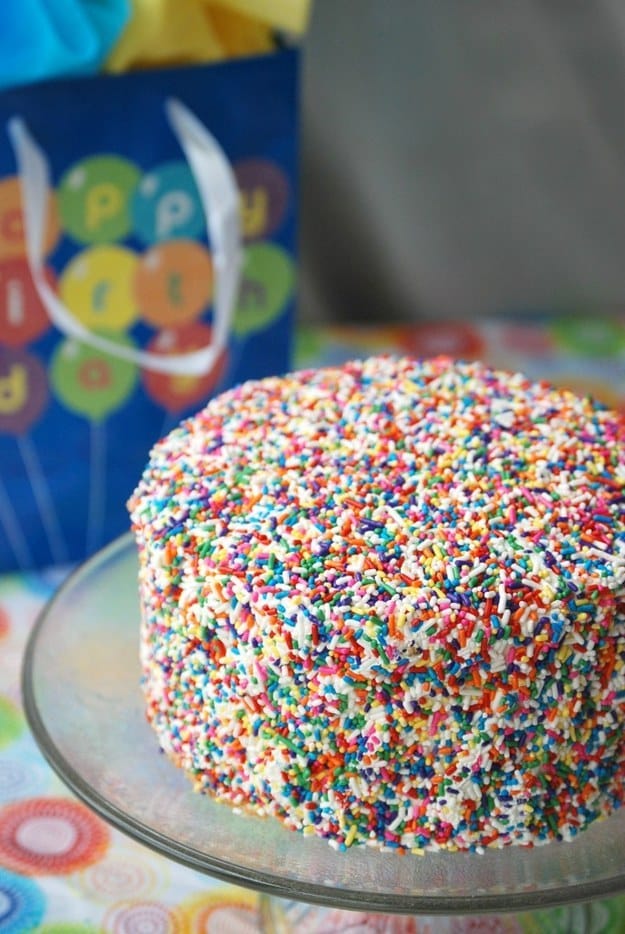 Coat a cake with sprinkles.