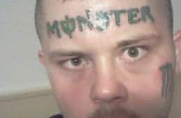 A man with a tattoo of the logo for the energy drink brand Monster on his forehead