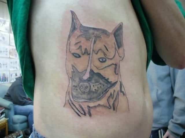 A picture showing a really badly drawn tattoo of a dog on someone’s body 