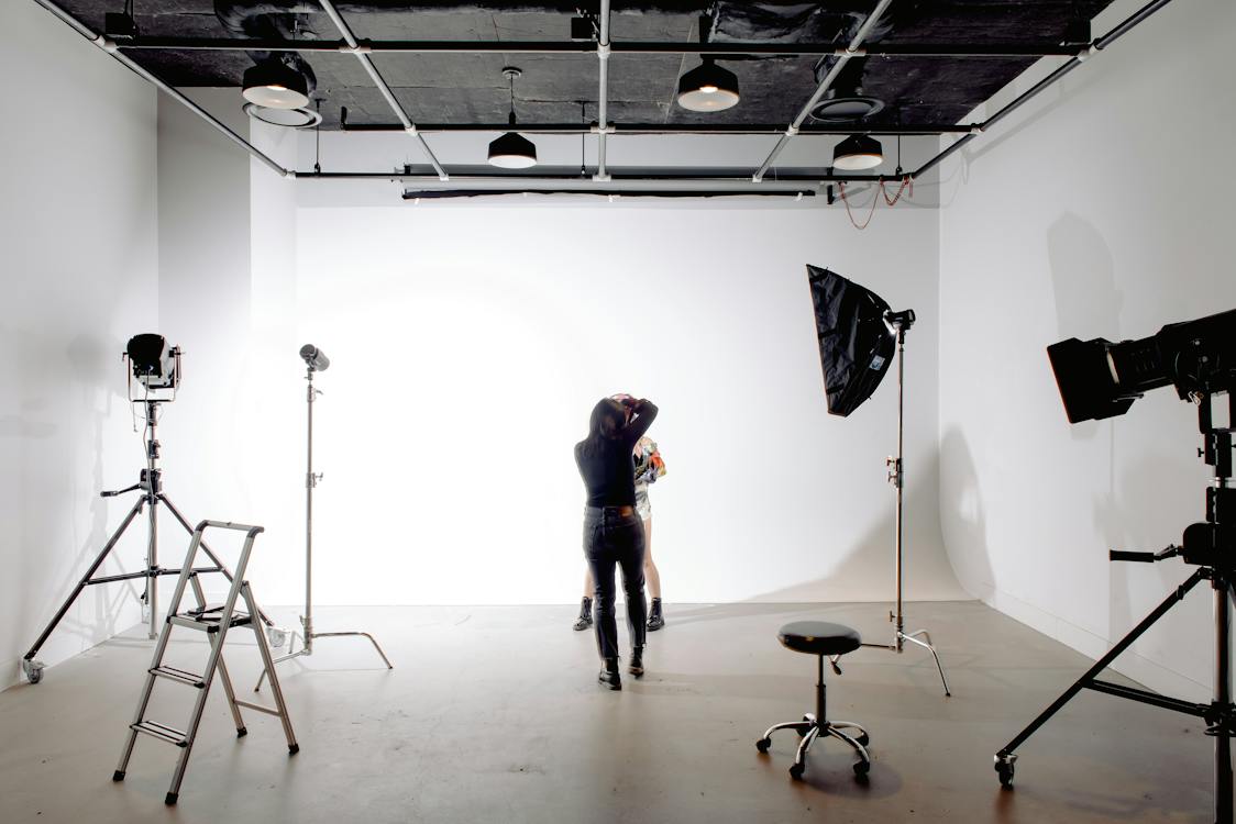 Free Back view of unrecognizable professional photographer taking photo of anonymous model in modern light studio Stock Photo